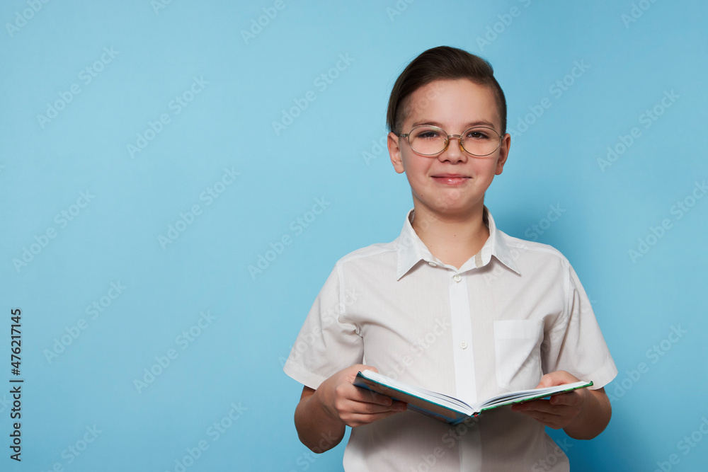 Obraz premium Portrait school boy with a book over blue background