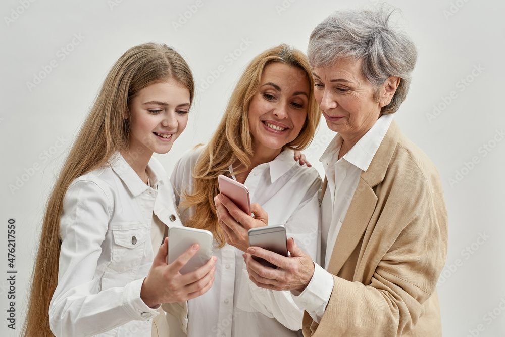 Smiling three females use and watch smartphones Smiling three females use and watch smartphones