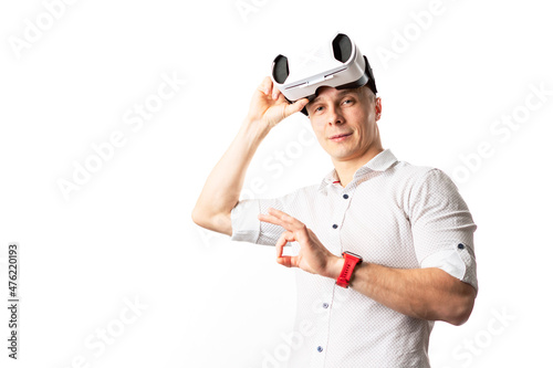 A successful man in a white vr helmet in a white shirt on a white background shows an OK sign.