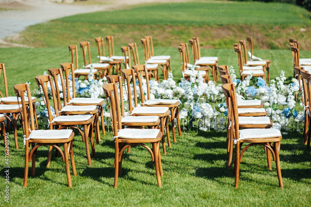 Incredibly beautiful outdoor ceremony on green grass and wooden chairs and fresh flowers. Wedding day
