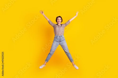 Full size photo of young excited cheerful woman have fun jump wear casual outfit isolated over yellow color background