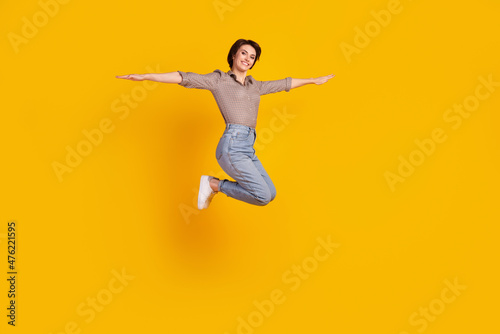 Full size profile side photo of young pretty woman jump up fly hands plane isolated over yellow color background