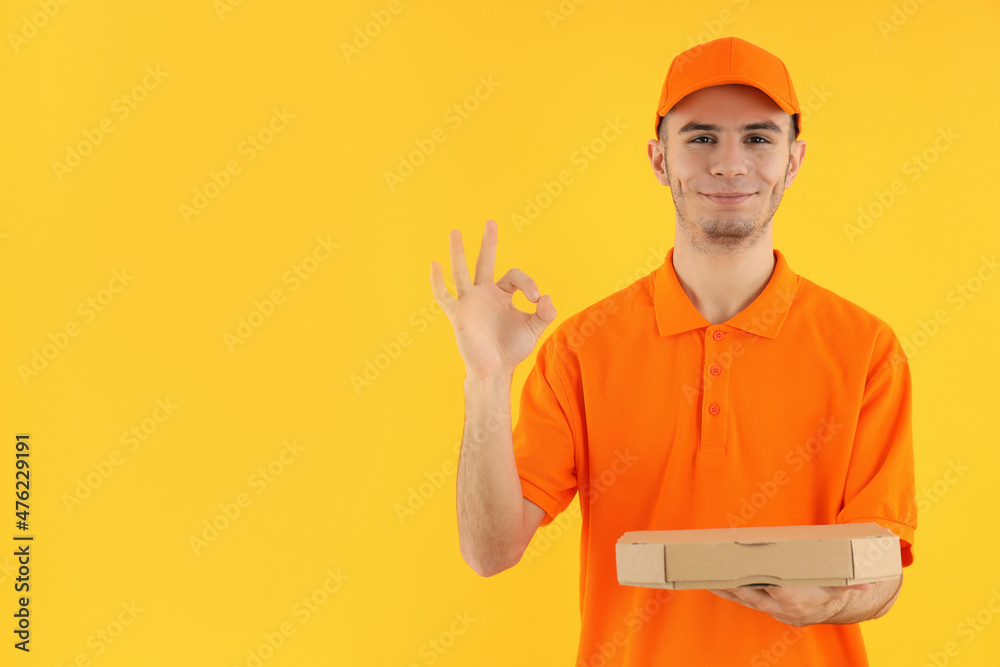 Attractive delivery man with pizza box on yellow background Attractive delivery man with pizza box on yellow background