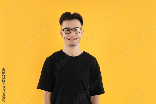 Young man in glasses on yellow background