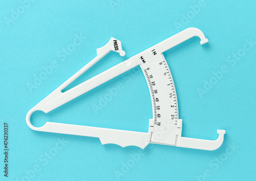 White caliper on blue background. Overhed. Slimming treatment concept. photo