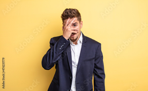 businessman looking shocked, scared or terrified, covering face with hand