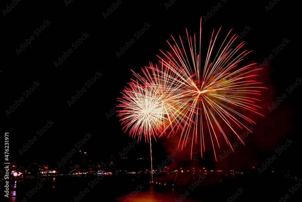 Spectacular red and gold fireworks exploding in to the night sky over the bay