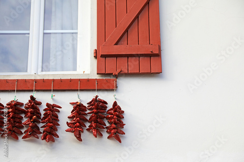 Canvas-taulu espelette pimientos rojos colgados el la fachada de una casa con ventanas rojas