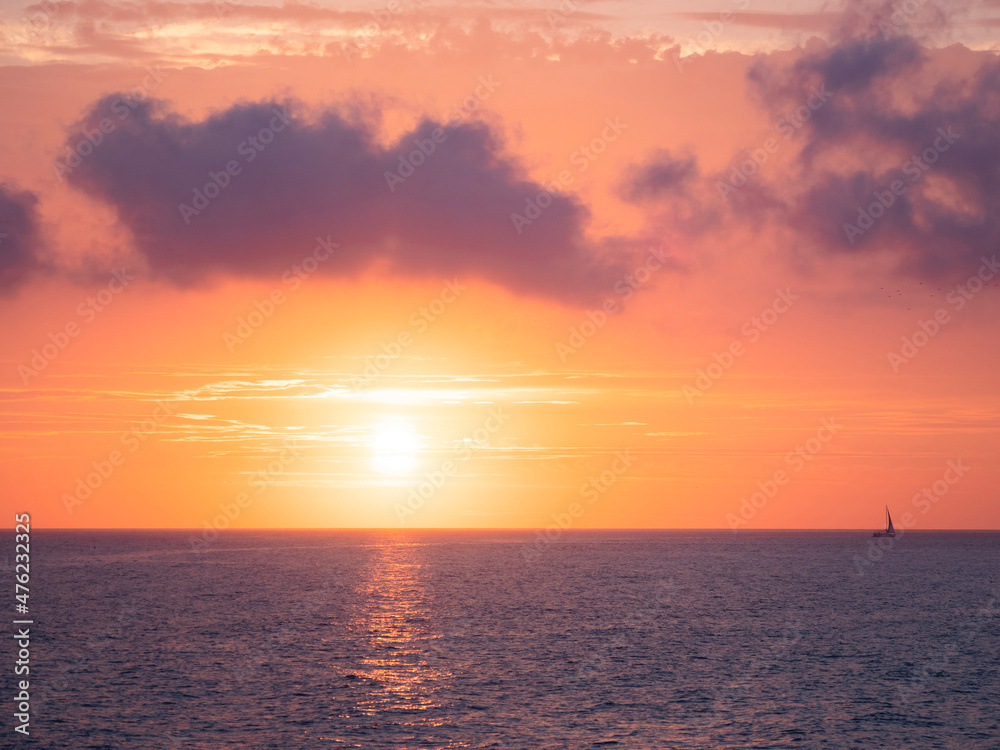 Fototapeta premium Gorgeous sunset over Black sea. Sailing yacht on orange sky with colorful clouds background. Sochi, Russia.