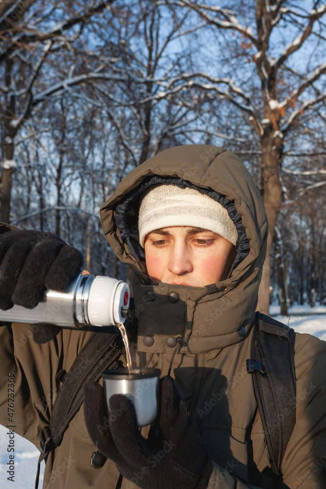 Man drinks hot tea from metal thermos. Leisure activity in winter forest at sunset. Man drinks hot tea from metal thermos. Leisure activity in winter forest at sunset.