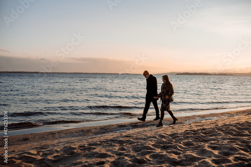 Young beautiful couple on a walk by the sea in autumn in the off-season, hugging, walking, smiling
