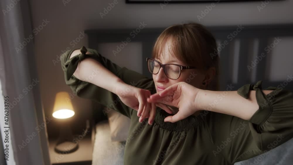 Sleepy Young Woman With Glasses Waking Up and Stretching Arms on Bed on Bright Sunny Morning, Close Up Sleepy Young Woman With Glasses Waking Up and Stretching Arms on Bed on Bright Sunny Morning, Close Up