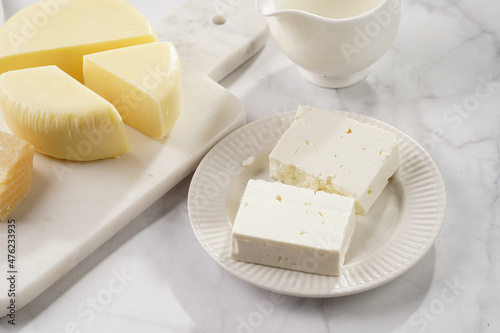 Various cheese types on marble and porcelain plates - ingredients for traditional georgian open pie khachapuri photo