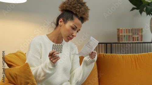 Beautiful black woman reads the medical instructions for pills. A woman holding a painkiller