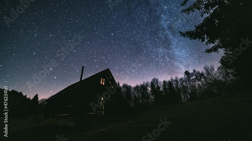 Time lapse Fairytale night sky with millions stars of milky way galaxy above wooden hut in wild forest nature Astronomy photo