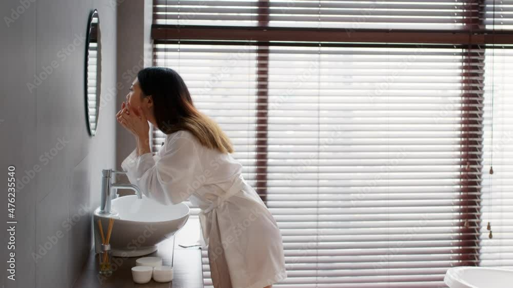 Problem Skin. Asian woman looking at mirror and popping pimple on face