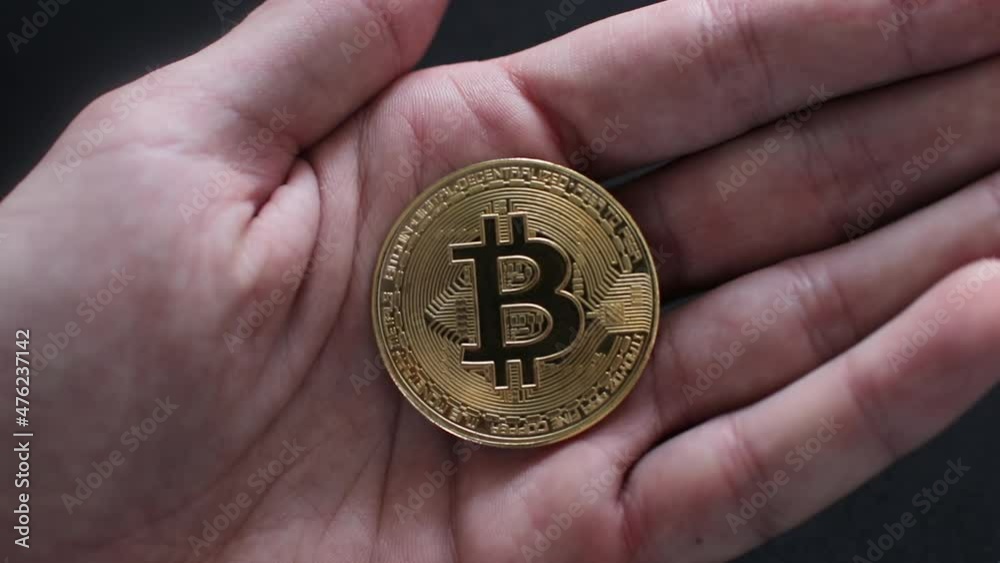 Male hand holding a gold coin bitcoin, close up. Bitcoin cryptocurrency. Male hand holding a gold coin bitcoin, close up. Bitcoin cryptocurrency.
