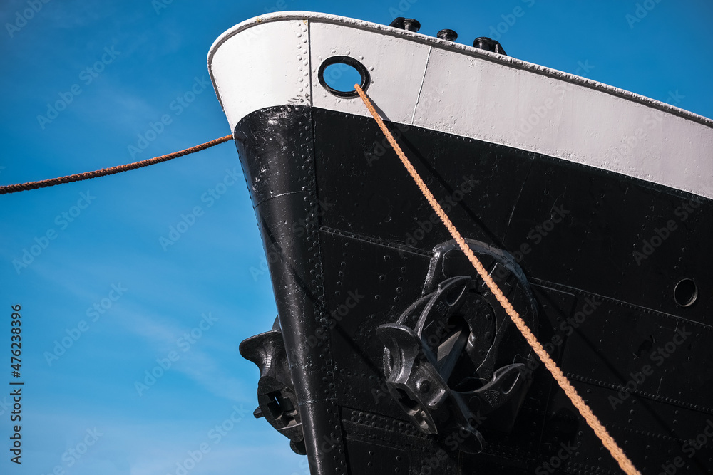 the front part of a moored huge ship liner against the blue sky close-up bottom view