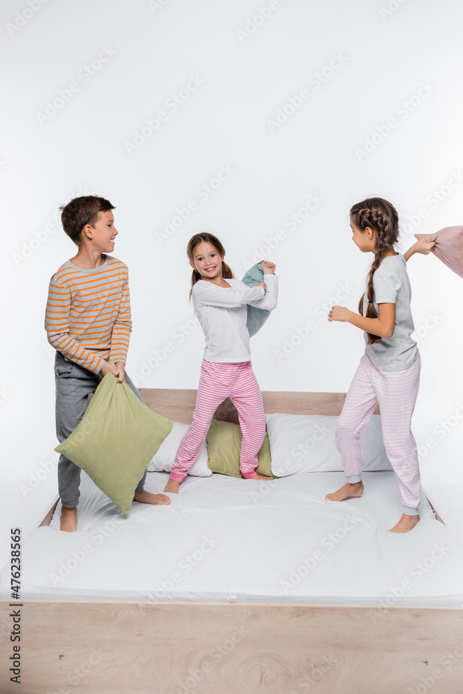 happy kids having pillow fight while standing isolated on white.