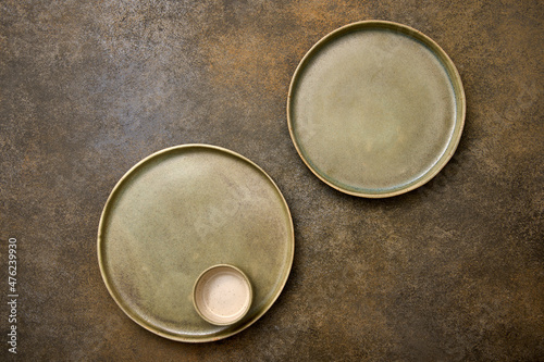 Flat lay empty green ceramic two plates and saucepan on rustic background, copy space