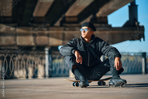 Skater male relax sitting on skateboard on street urban background