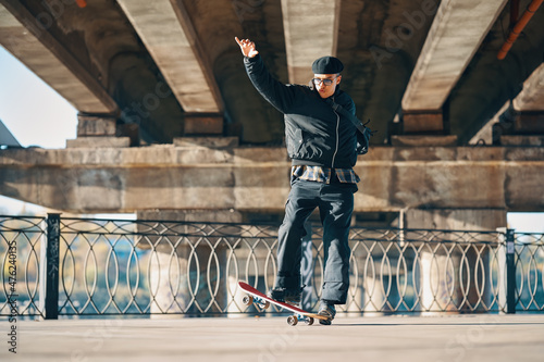 Skateboarder does ollie trick on street urban background photo