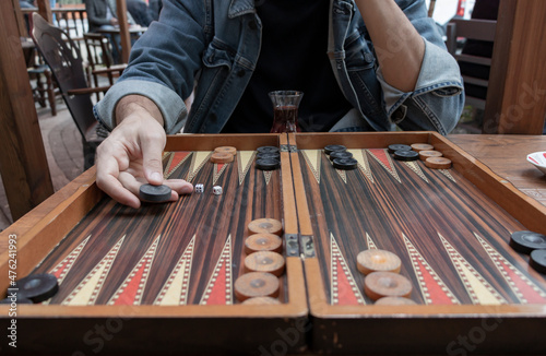Canvastavla Close up man hand holding backgammon checker and playing backgammon at outside