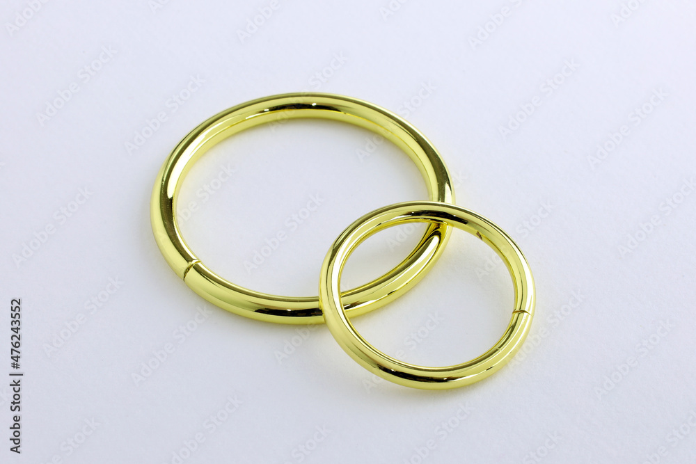 Large and small metal rings on a white background. Metallic gold chrome rings for making bags and backpacks. High quality sewing accessories. Large and small metal rings on a white background. Metallic gold chrome rings for making bags and backpacks. High quality sewing accessories.