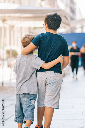 Two brothers or friends hugging  each other walking and playing in the street of a city © Michele Ursi