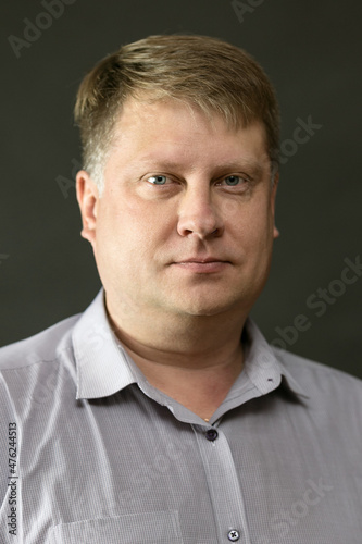 Portrait of an adult male history teacher black background in a blue shirt.