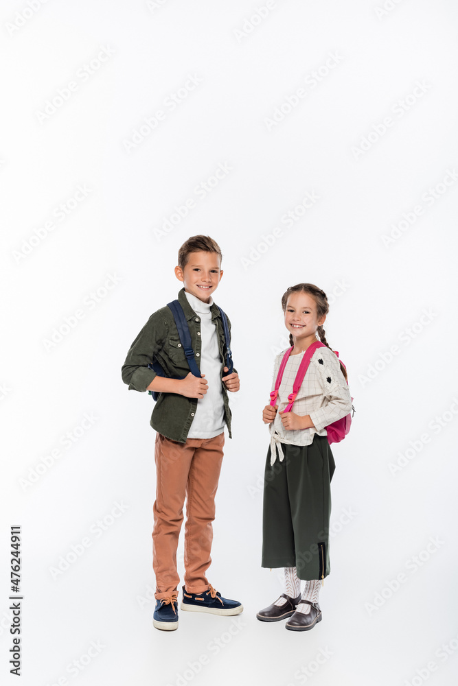 cheerful schoolkids standing with backpacks isolated on white.