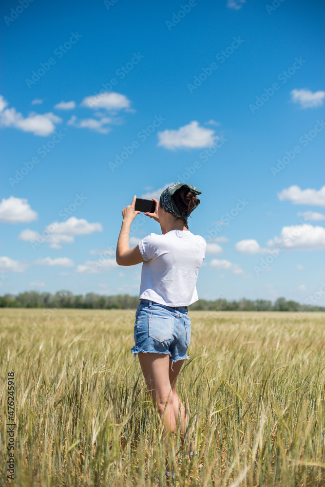 a young girl stands in a wheat field and takes pictures a young girl stands in a wheat field and takes pictures
