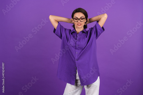 Young woman in a shirt with short sleeves on a purple background, with makeup, lipstick on her lips and stylish glasses posing on the background