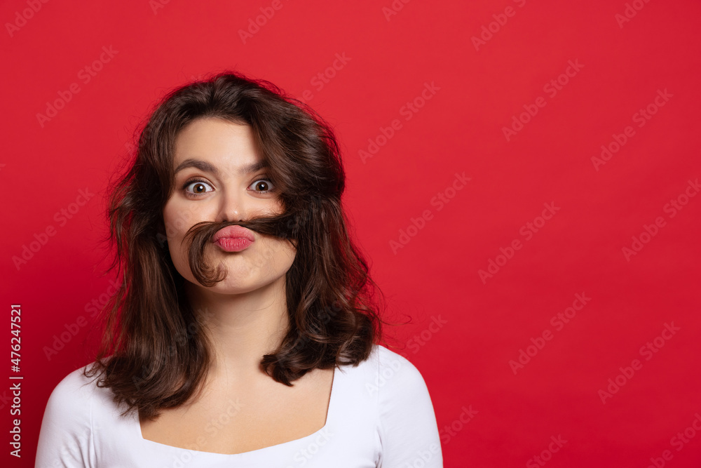 Close-up young funny cute girl making faces isolated on red color background. Concept of emotion, facial expression. Close-up young funny cute girl making faces isolated on red color background. Concept of emotion, facial expression.