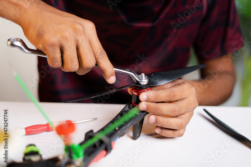 Close up shot professional engineer removing propeller by using spanner while repairning drone or uav at workplace - concept of quadcopter repair service.