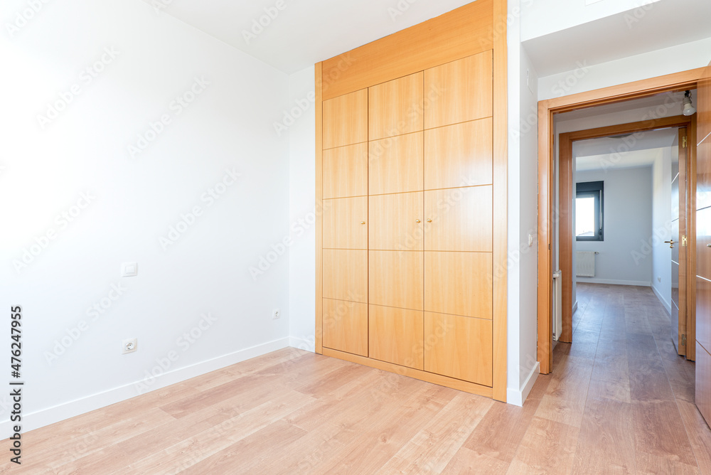 Empty bedroom with three section wardrobe in cherry wood with oak parquet flooring