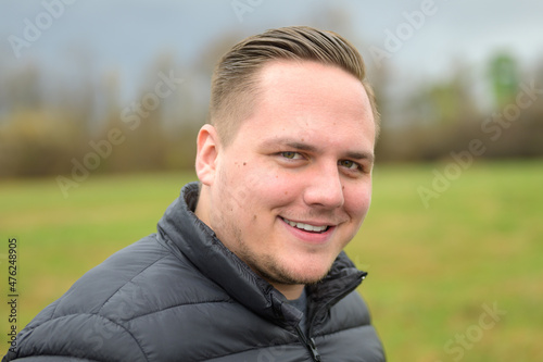 Portrait of a young man looking at camera with quiet smile © michaelheim