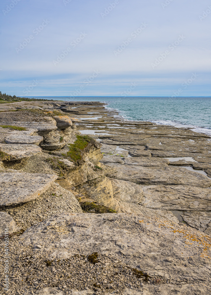 the rugged shoreline of the St Lawrence estuary, with rocky formations sculpted by erosion near Cap Ferré waterfall in Havre St Pierre, in Cote Nord region of Quebec, Canada