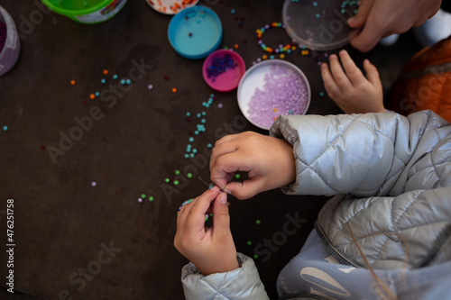 little children's hands weave a bead bracelet close-up shot