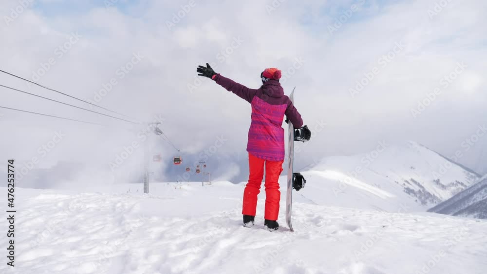 A young woman on a snowboard on top mountain on a ski track. Getting ready for skiing on a snowy slope. Winter travel at the ski resort. Concept of active recreation in winter. A young woman on a snowboard on top mountain on a ski track. Getting ready for skiing on a snowy slope. Winter travel at the ski resort. Concept of active recreation in winter.