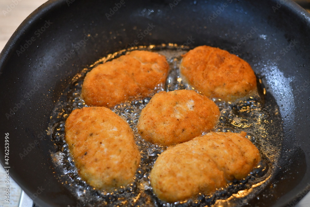 fried cutlets in a pan. Breaded parmesan chicken browning in wrought