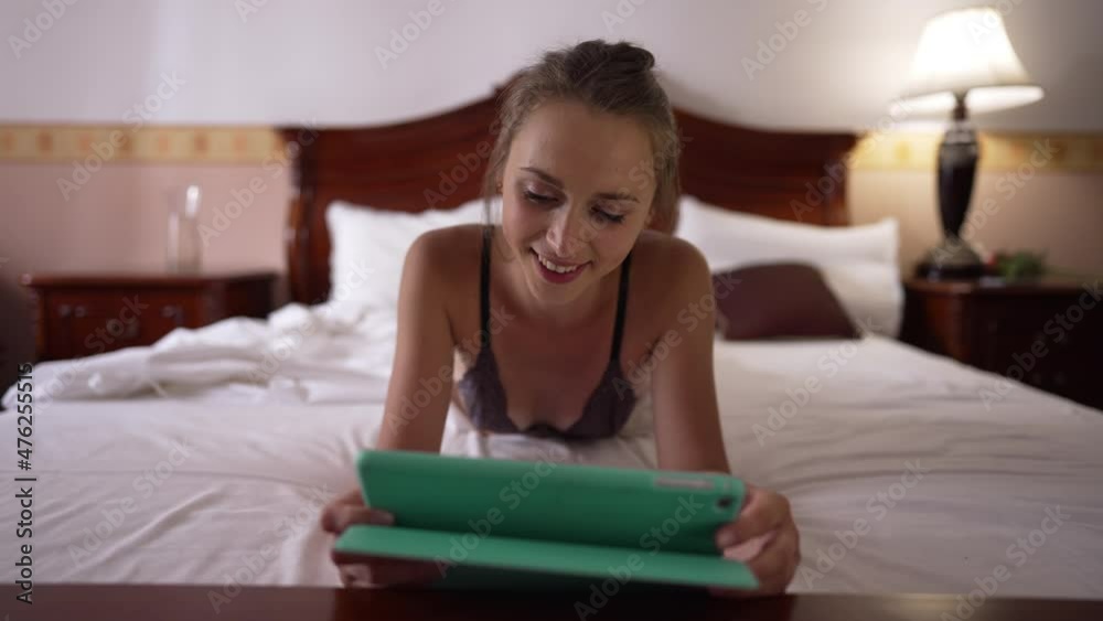 Front view portrait happy relaxed young woman in bra lying on bed surfing Internet on tablet smiling. Caucasian slim gorgeous brunette lady enjoying leisure in bedroom at home. Femininity and joy Front view portrait happy relaxed young woman in bra lying on bed surfing Internet on tablet smiling. Caucasian slim gorgeous brunette lady enjoying leisure in bedroom at home. Femininity and joy
