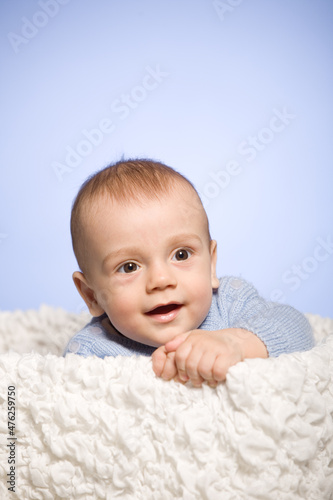 Happy baby, brown eyed infant peeking out of the box, portrait of a laughing six month old boy, studio shooting, vertical