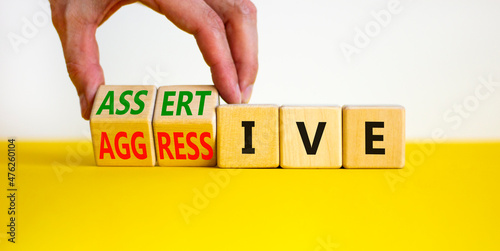 Aggressive or assertive symbol. Businessman turns wooden cubes, changes the word Aggressive to Assertive. Beautiful white background, copy space. Business, psychological aggressive assertive concept.