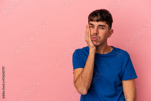 Young mixed race man isolated on pink background who feels sad and pensive, looking at copy space.