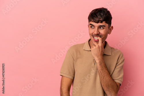 Young mixed race man isolated on pink background relaxed thinking about something looking at a copy space.
