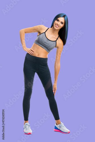 Full body portrait image of young happy smiling bright vivid blue haired slim woman doing fitness stretching exercise, isolated over violet purple color background
