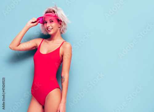 Fotografie, Obraz Portrait of young smiling blond model in summer swimwear red bathing suit and transparent visor cap