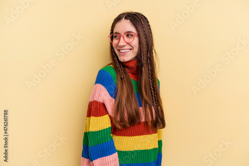 Young caucasian woman isolated on yellow background looks aside smiling, cheerful and pleasant.