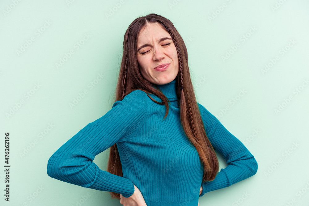 Young caucasian woman isolated on green background suffering a back pain. Young caucasian woman isolated on green background suffering a back pain.